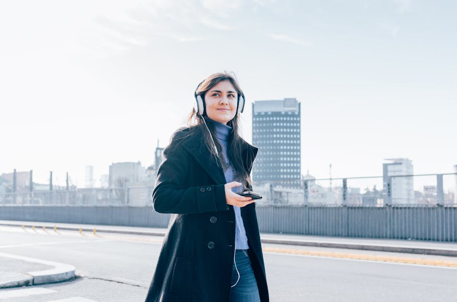 Woman walking while listening to headphones.