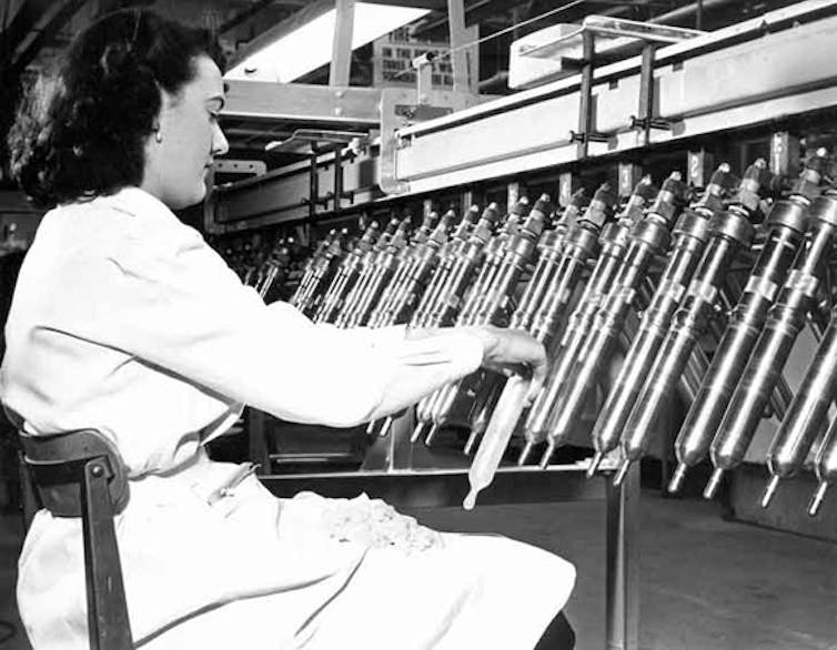 A woman in white tests condoms on an automated production line.