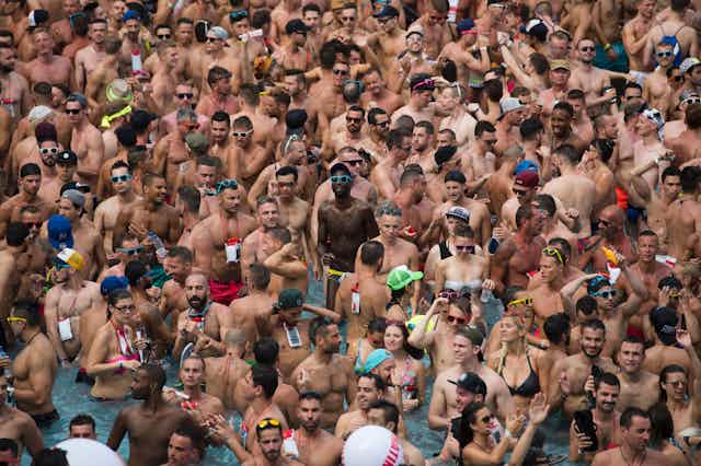 A throng of partygoers party in a swimming pool.