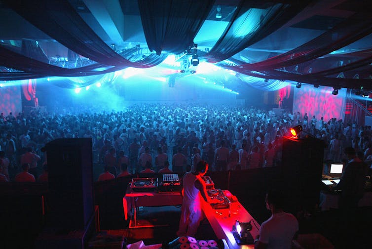 A DJ plays for a crowd dressed in white.