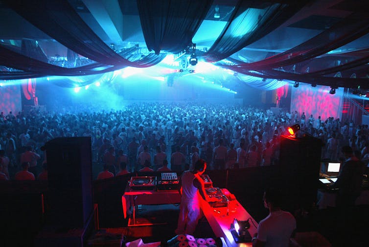 A DJ plays for a crowd dressed in white.