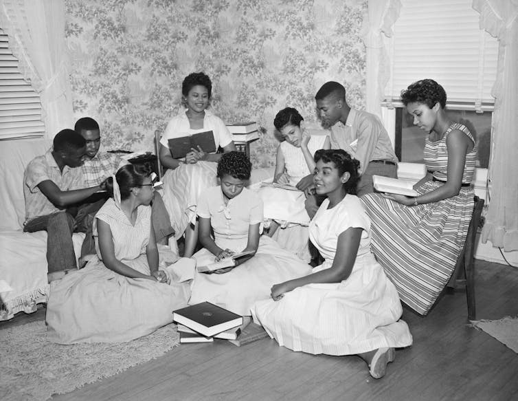 A group of African American students read books together in a small room.