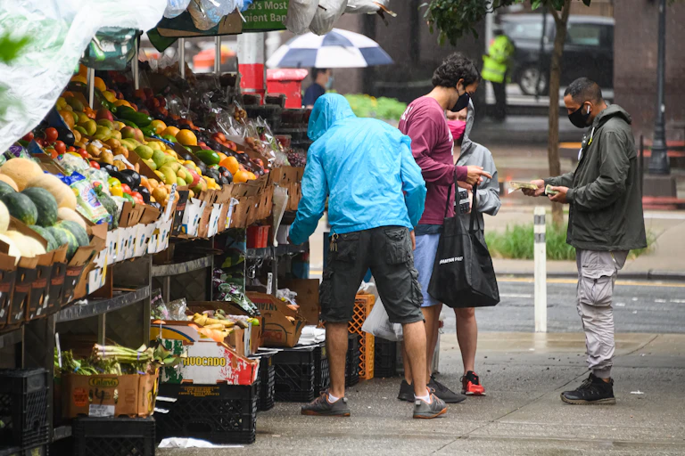 People shop at vegetable stand in New York City.