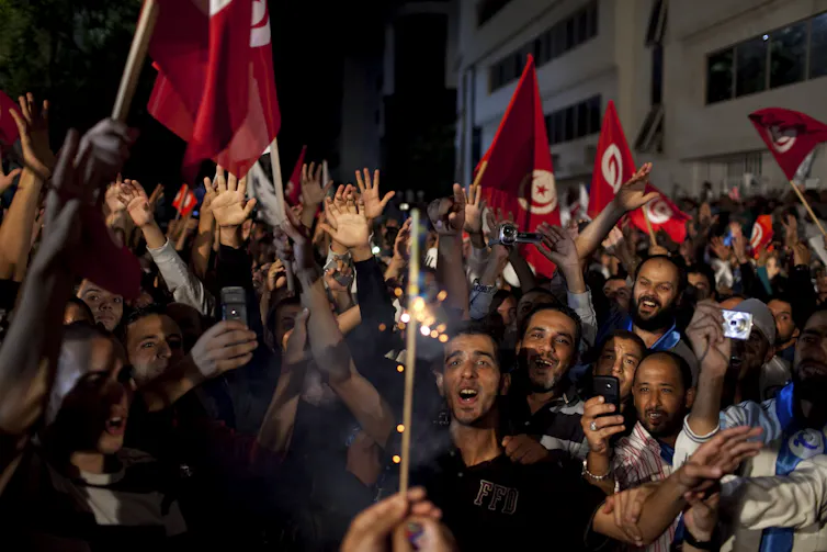 A happy crowd waving Tunisian flags celebrates the election of October 2011.
