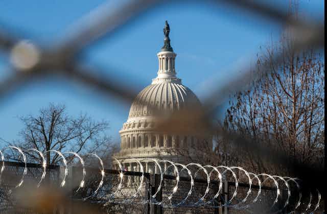 View of the US Capitol with barbed wire in the foreground.