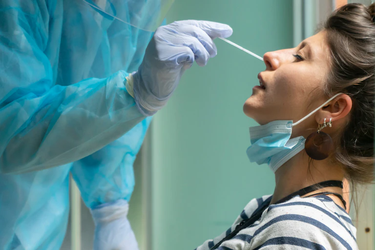 A health worker administering a nasal swab to a woman