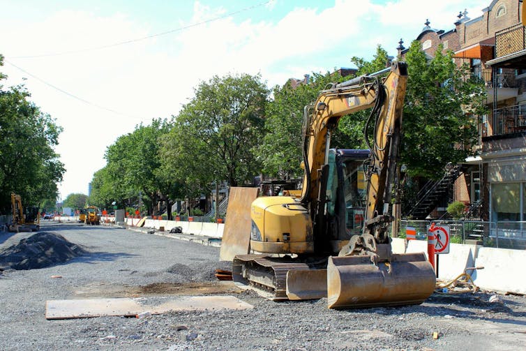 An excavator on an urban tree-lined street