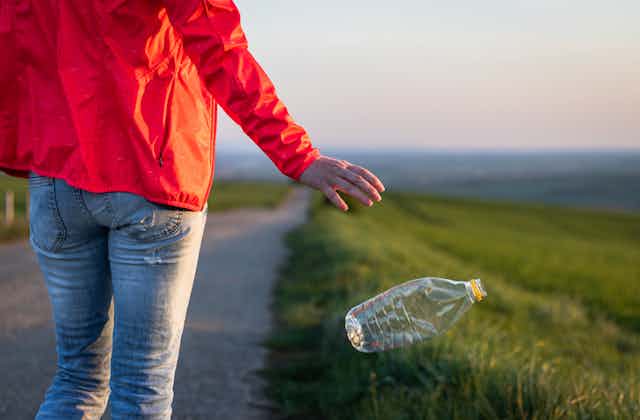 A person drops litter on a green field.