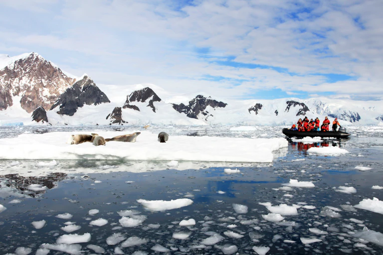 Inflatable boat full of tourists, watching seals on an ice berg