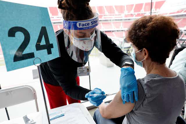 Person being vaccinated by a health worker in a stadium in the United States