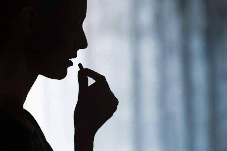 Close up of young woman taking prescription pill.