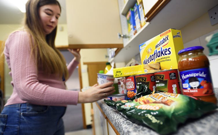 Woman picking up a container from a shelf of food at a food bank