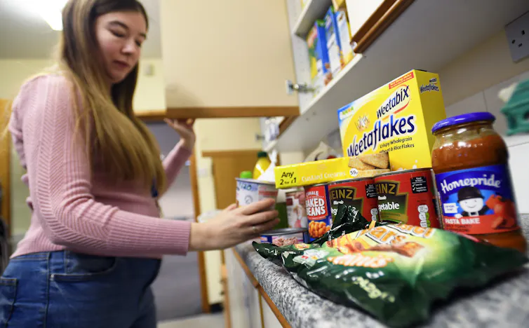 Woman picking up a container from a shelf of food at a food bank