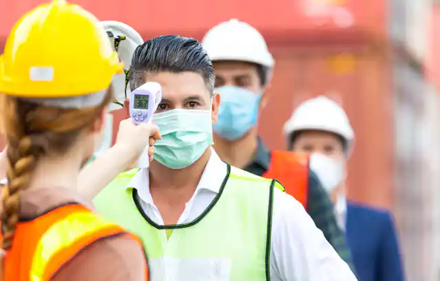 Builders having the temperature checked using an infrared scanner