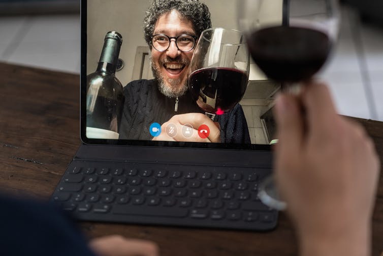 Two people on a videocall drinking red wine