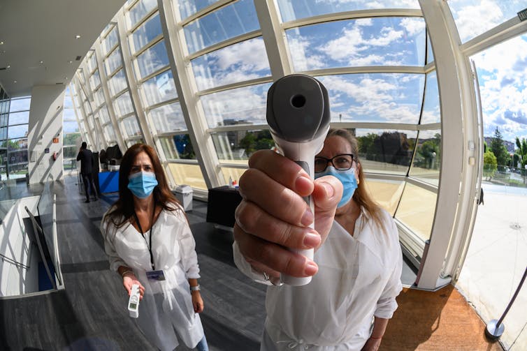 A woman holding an infrared scanner up to face the camera