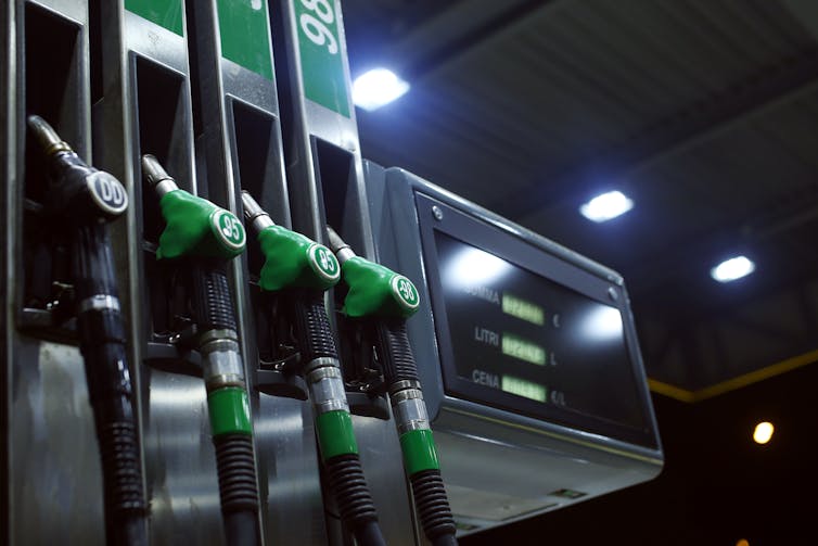 A row of petrol pumps on a station forecourt at night.