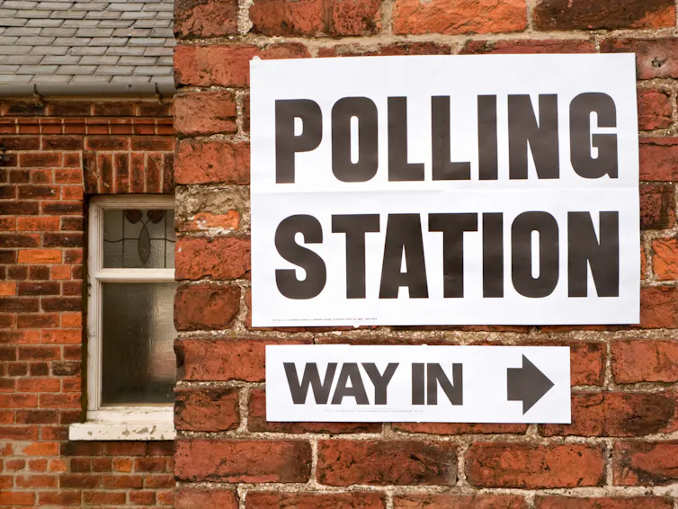 A sign directing people to a polling station stuck on a wall.