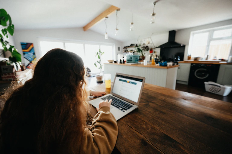 A girl sitting at a computer in the dining room