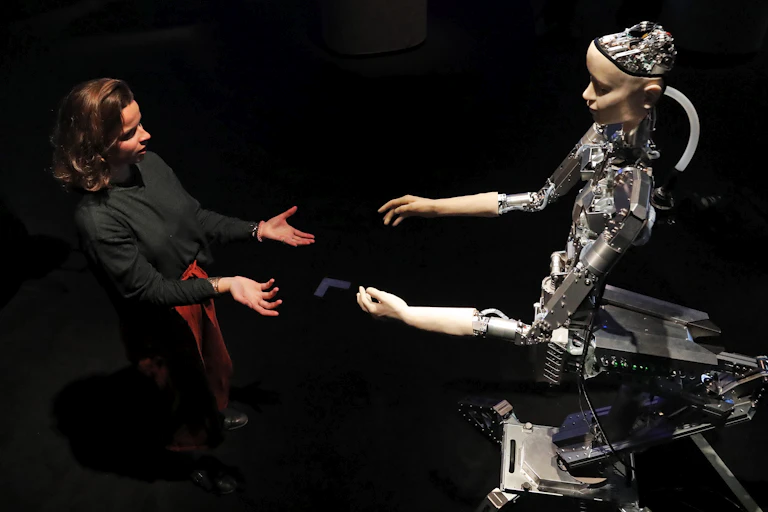 A woman and a humanoid robot reach out to each other