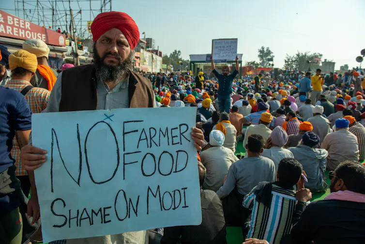 Man holds sign saying 'No farmer food. Shame on Modi'