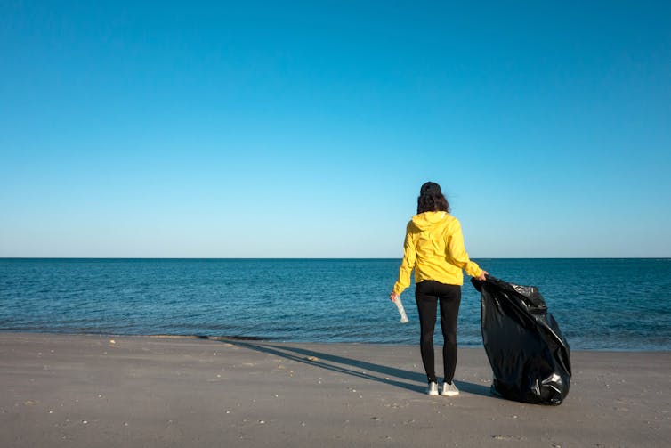 A person cleans up rubbish on the beach.