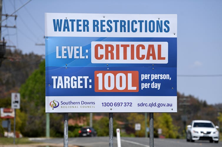 A sign that says 'water restrictions, level: critical, target: 100L'
