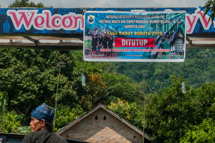 Laki-laki di bawah spanduk penutupan wisata Baduy.