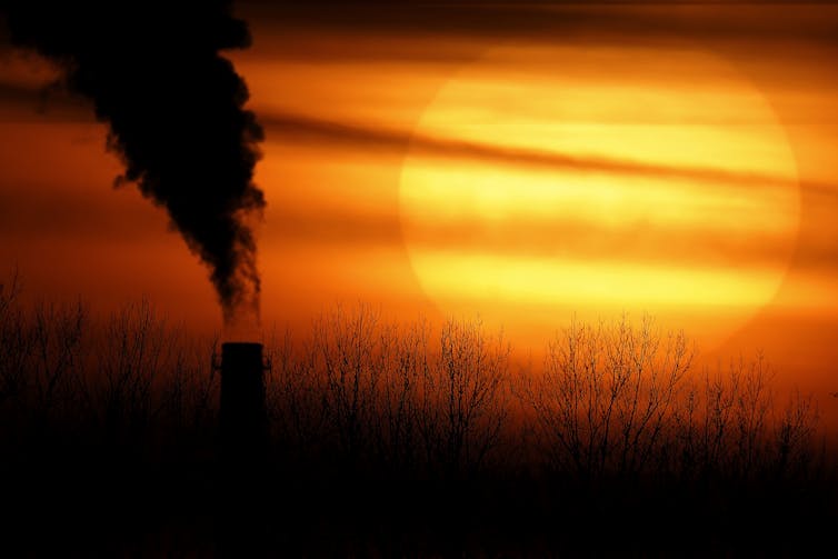 smoke form industrial chimney against setting sun