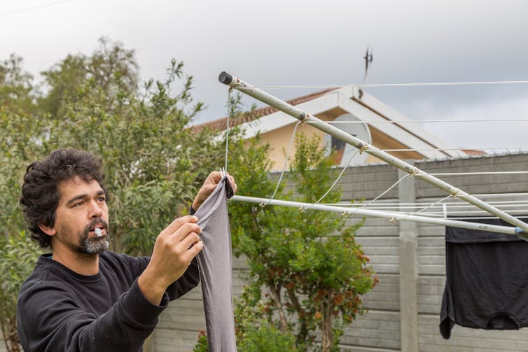 A man hangs washing on a washing line.