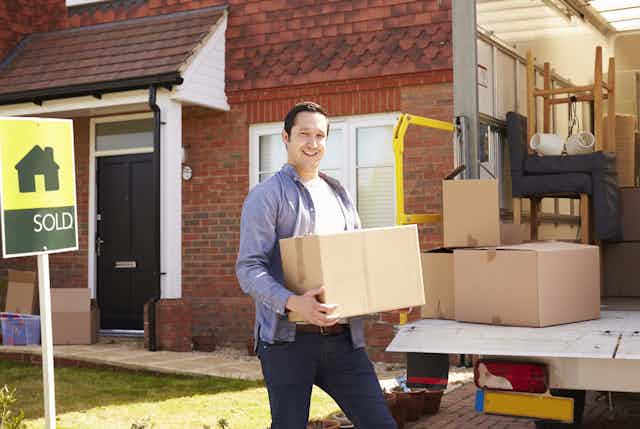Man loading truck with household goods in front of sold house