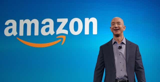Jeff Bezos, fundador de Amazon, sonríe delante de su logotipo.