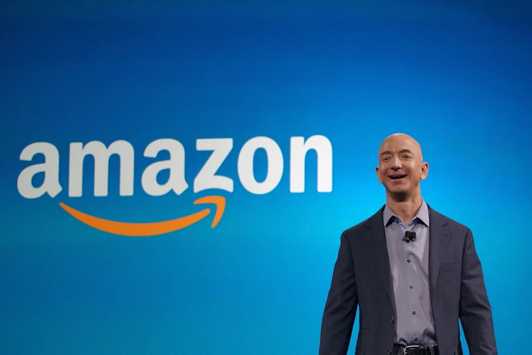 Jeff Bezos, fundador de Amazon, sonríe delante de su logotipo.