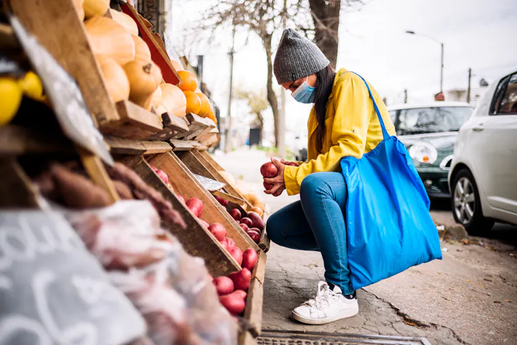 Woman choosing vegetables at greengrocer
