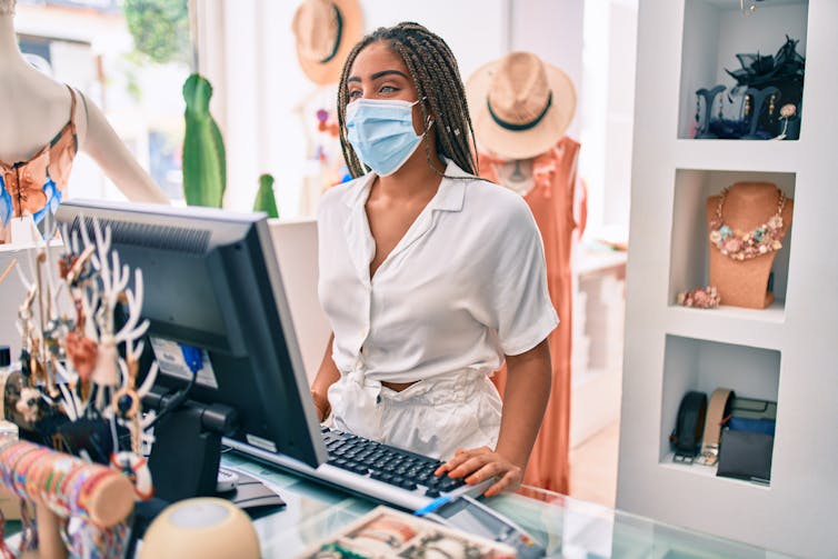 Woman wearing mask behind till in shop