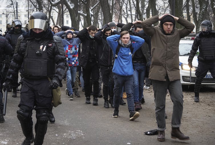 Detained protesters walk are escorted by police
