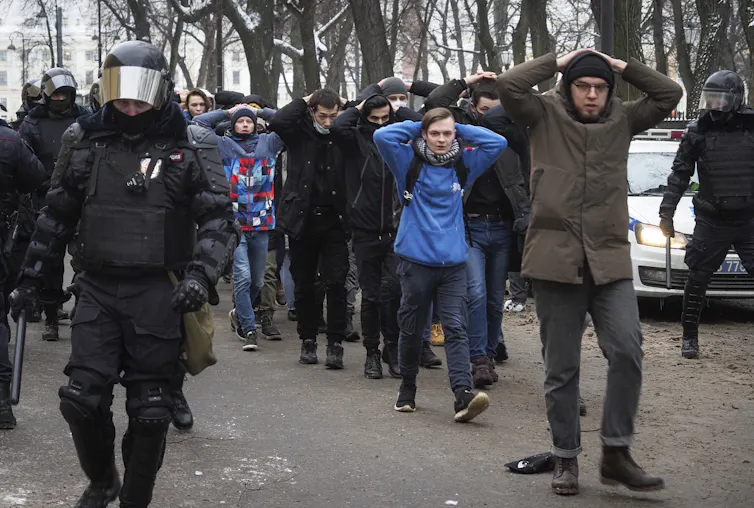Detained protesters walk are escorted by police