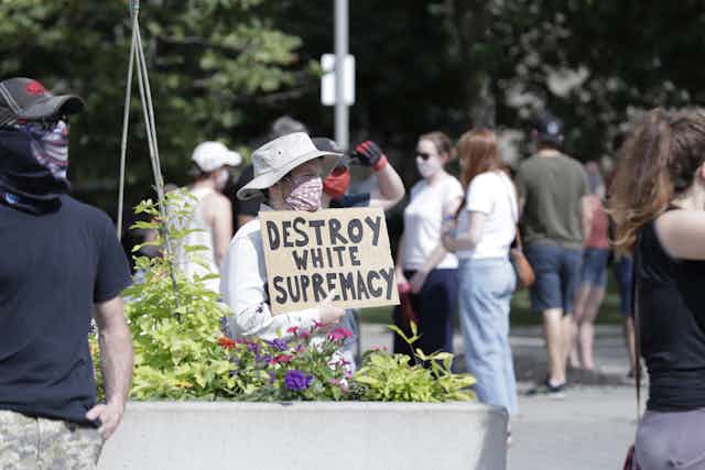 A man holding a sign that reads DESTROY WHITE SUPREMACY