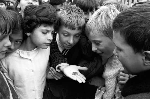 A photo from 1969 showing a group of children gathering to look at the new decimal 50 pence coin.