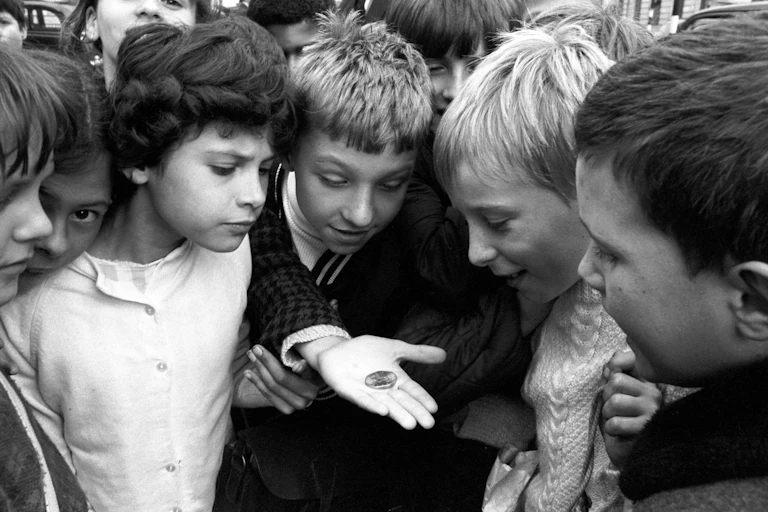 A photo from 1969 showing a group of children gathering to look at the new decimal 50 pence coin.