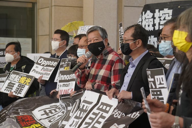 Men in masks carrying signs outside a courthouse.
