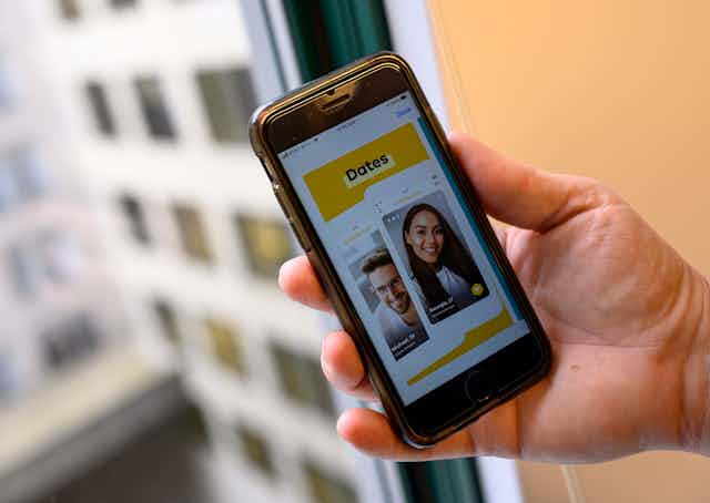 A hand holds an phone displaying the Bumble app.