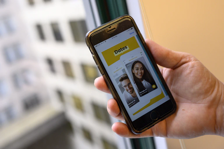 A hand holds an phone displaying the Bumble app.
