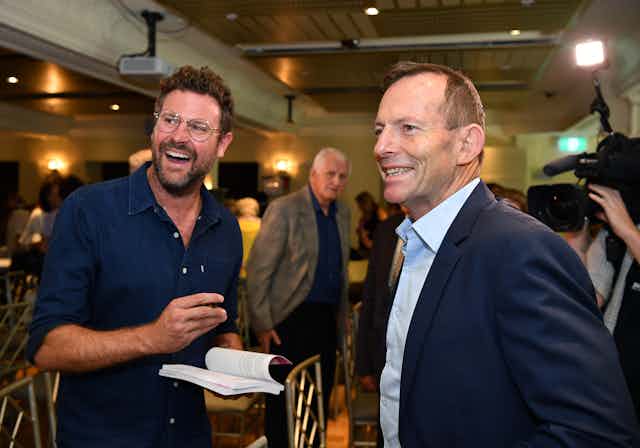 Johannes Leak signs a book for Tony Abbott during a book launch.