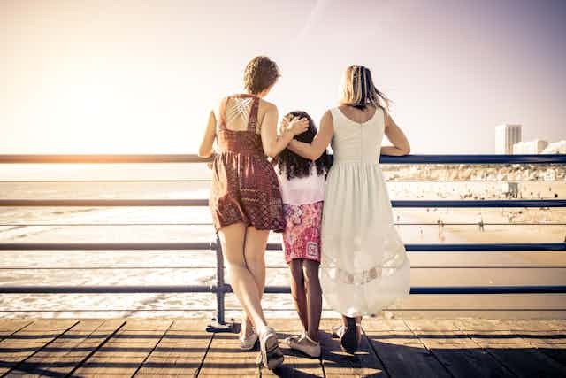 Two women with their daughter looking over a bridge.