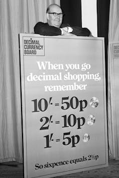 Lord Fiske, Chairman of the Decimal Currency Board, shown with a poster explaining how much new currency coins were worth.