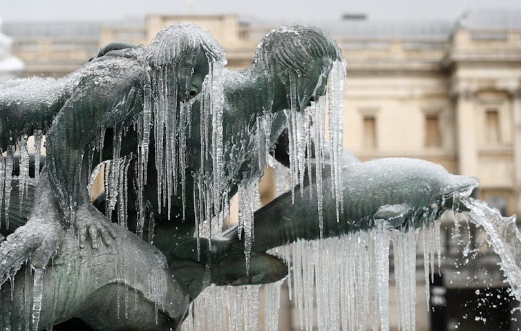 Icicles on a stone statue of people riding dolphins