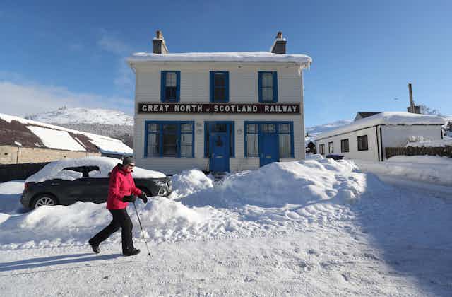 Woman walks down snowy street