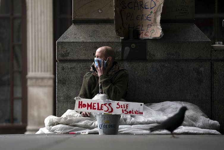 A homeless man wearing a mask