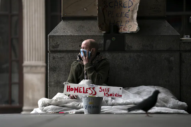 A homeless man wearing a mask